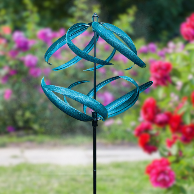 The Aqua Swirl Wind Spinner spinning gracefully in a garden with vibrant flowers, showcasing its dynamic motion and colorful design.